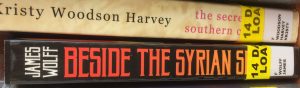 Two book spines, with the end of the titles obscured by stickers. The top one is by Kristy Woodson Harvey and reads 'the secre- southern c-'. The bottom is by James Wolff and reads 'Beside the Syrian S-'.